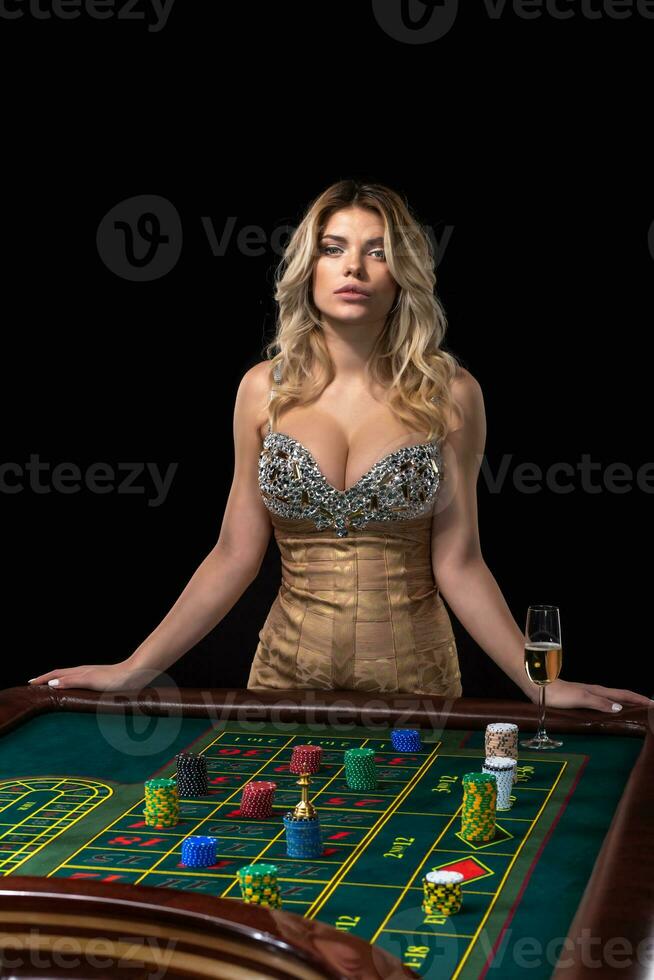 Young blonde woman wearing beautiful sexy shiny dress is playing roulette in the casino photo
