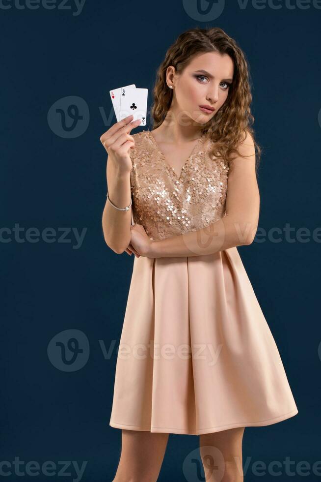 Young woman holding playing cards against dark background. Studio shot photo