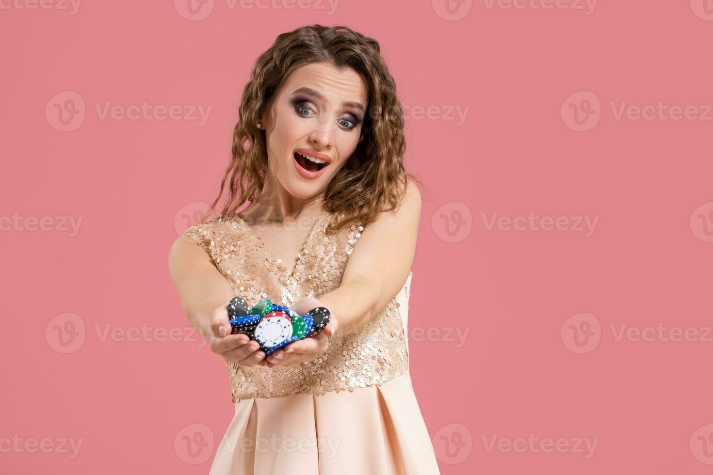 Smiling girl holding a gambling chips in her nands on pink background photo