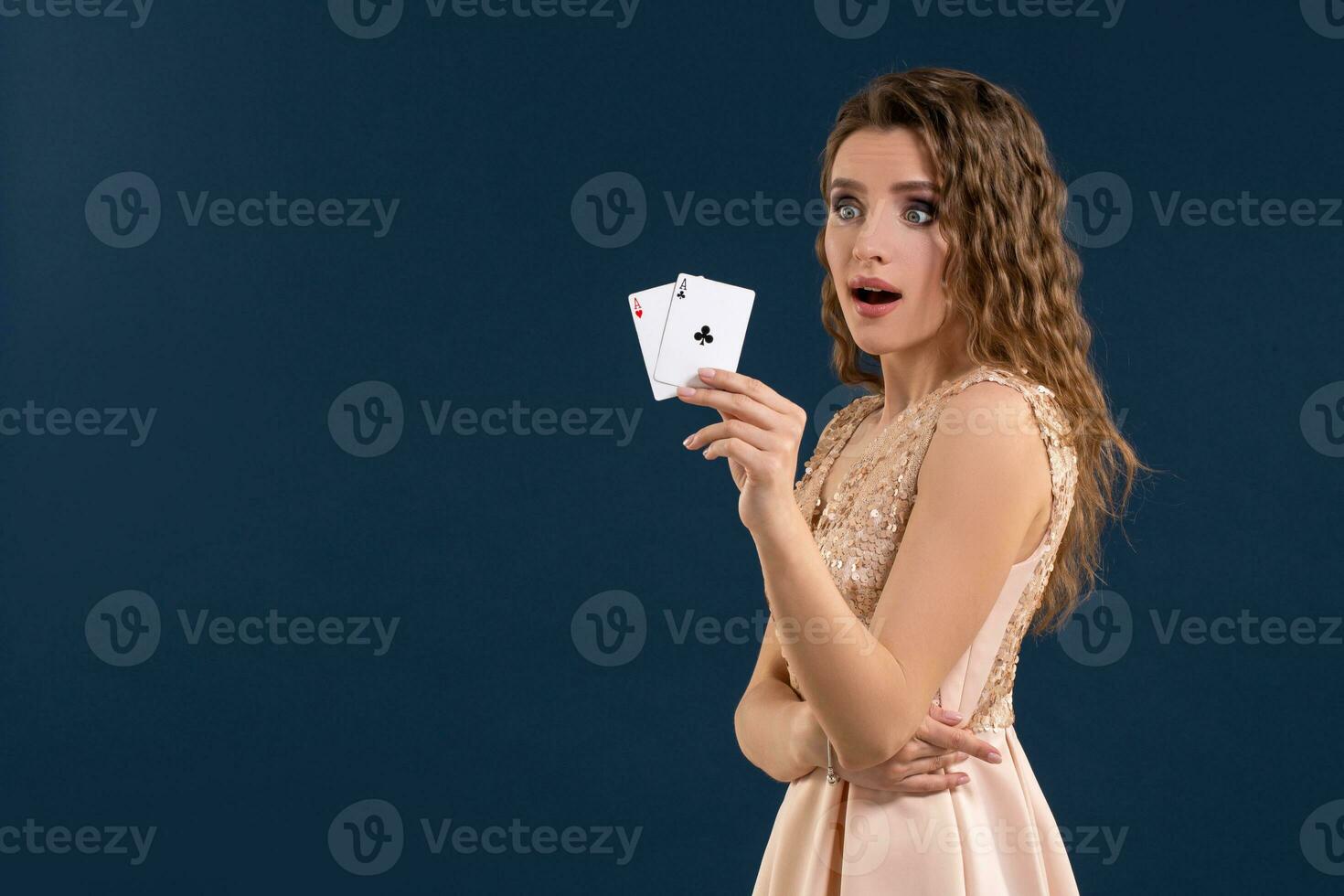 Young beautiful woman holding the winning combination of poker cards on dark blue background. Two aces photo