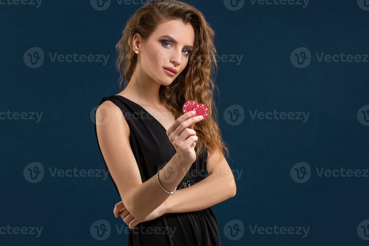 Portrait of the female gambler at the casino keeping poker chips in the hand photo