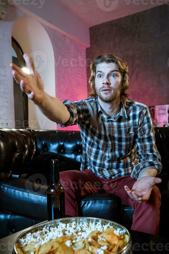 Young supporter man watching football game on television sitting photo