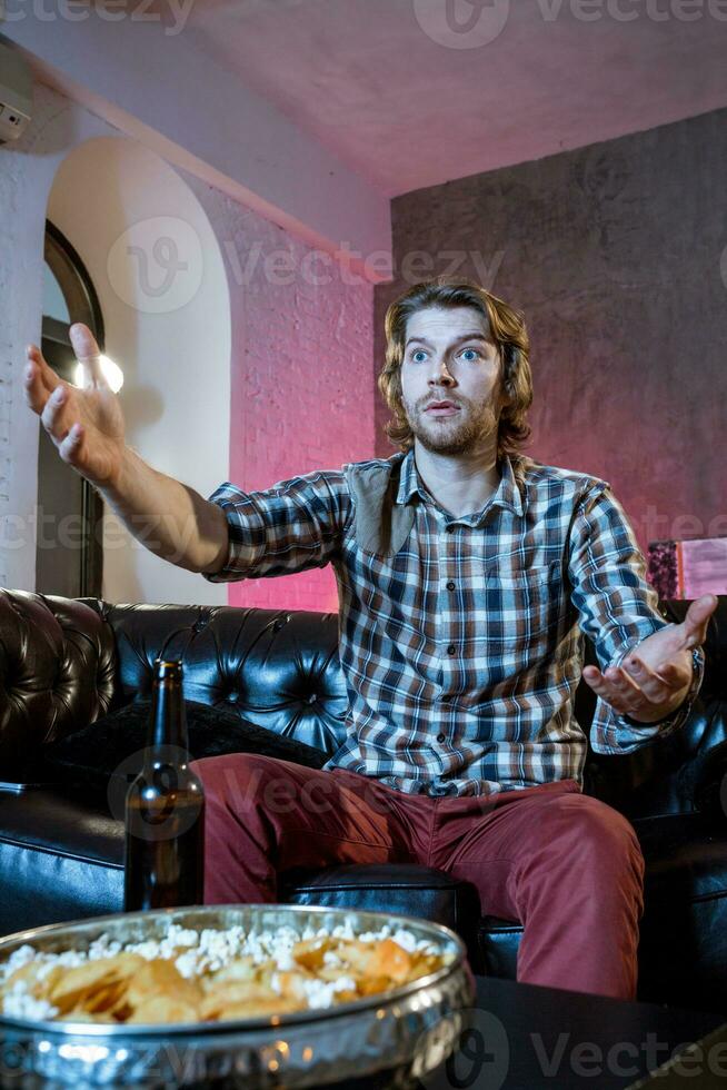 Young supporter man watching football game on television sitting photo