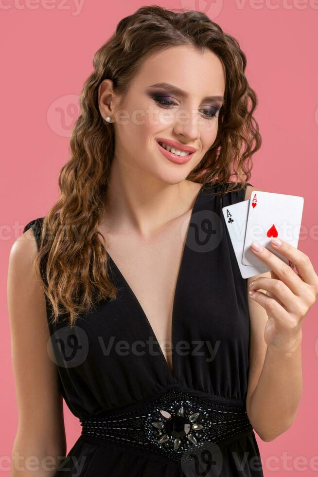 Young woman holding two aces in hand against on pink background photo