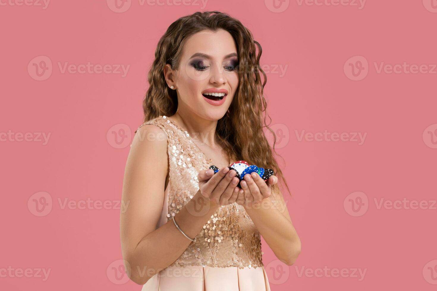 Smiling girl holding a gambling chips in her nands on pink background photo