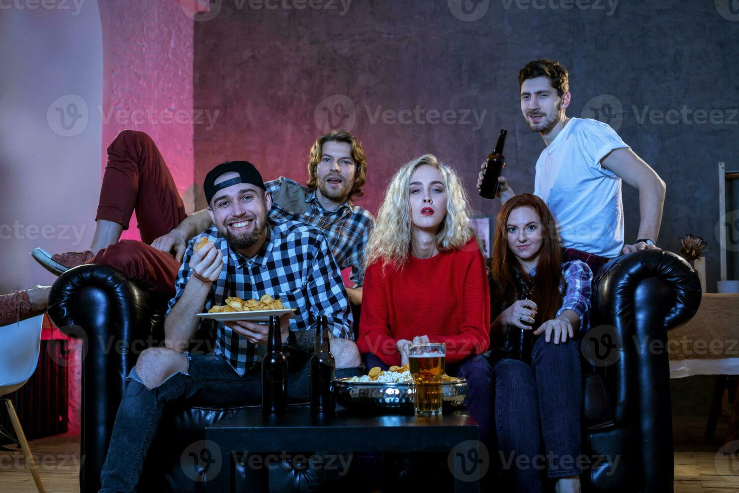 Five cheerful friends hanging out in an apartment and watching a photo