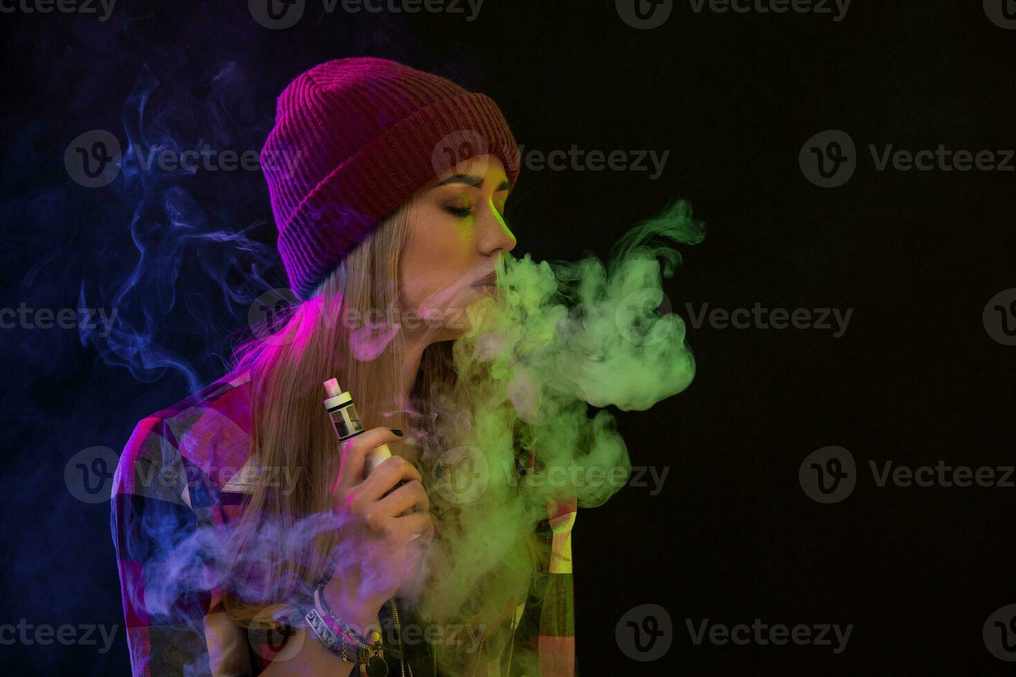 Vaping girl. Young hipster woman vape e-cig on black background. Hip-hop style. Studio shot photo