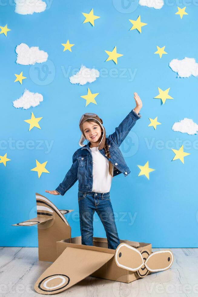 Little child girl in a pilot's costume is playing and dreaming of flying over the clouds. photo