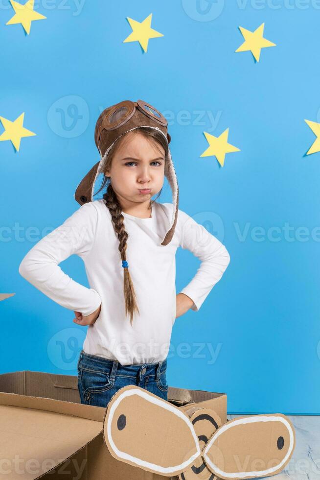 Little child girl in a pilot's costume is playing and dreaming of flying over the clouds. photo