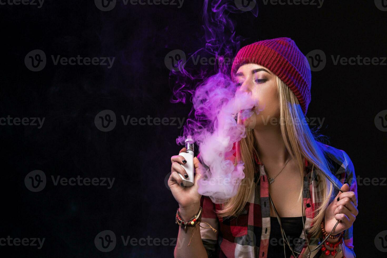 Vaping girl. Young hipster woman vape e-cig on studio on black background. Hip-hop style. Close up. photo