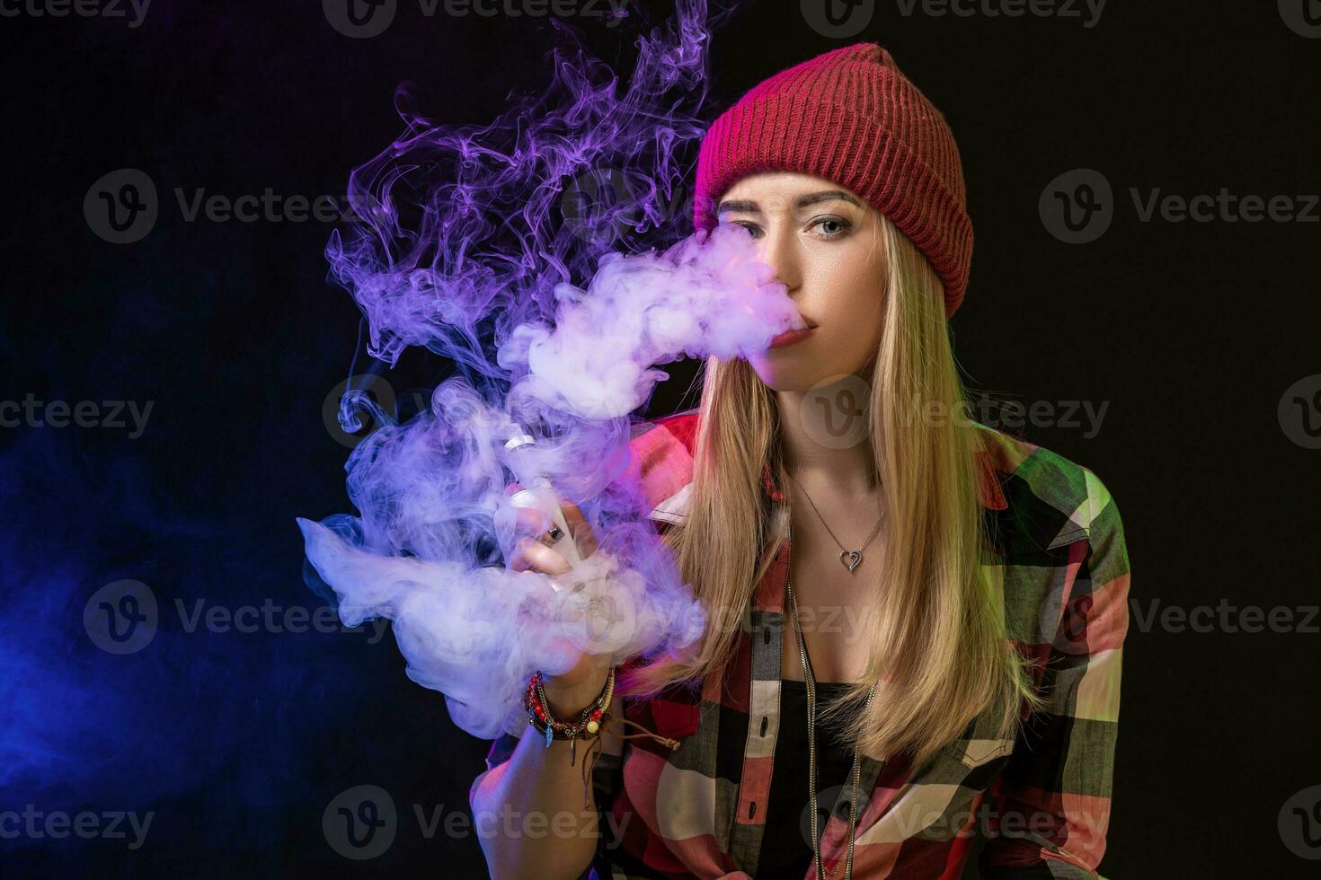 Vaping girl. Young hipster woman vape e-cig on studio on black background. Hip-hop style. Close up. photo