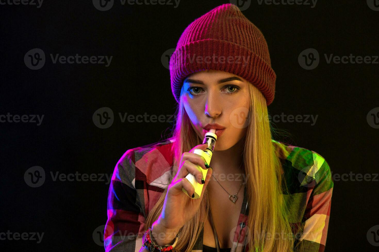 Vaping girl. Young hipster woman vape e-cig on studio on black background. Hip-hop style. Close up. photo