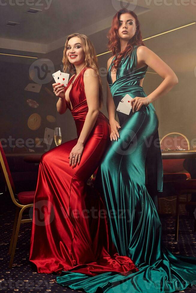 Two beautiful women are posing against a poker table in luxury casino. photo
