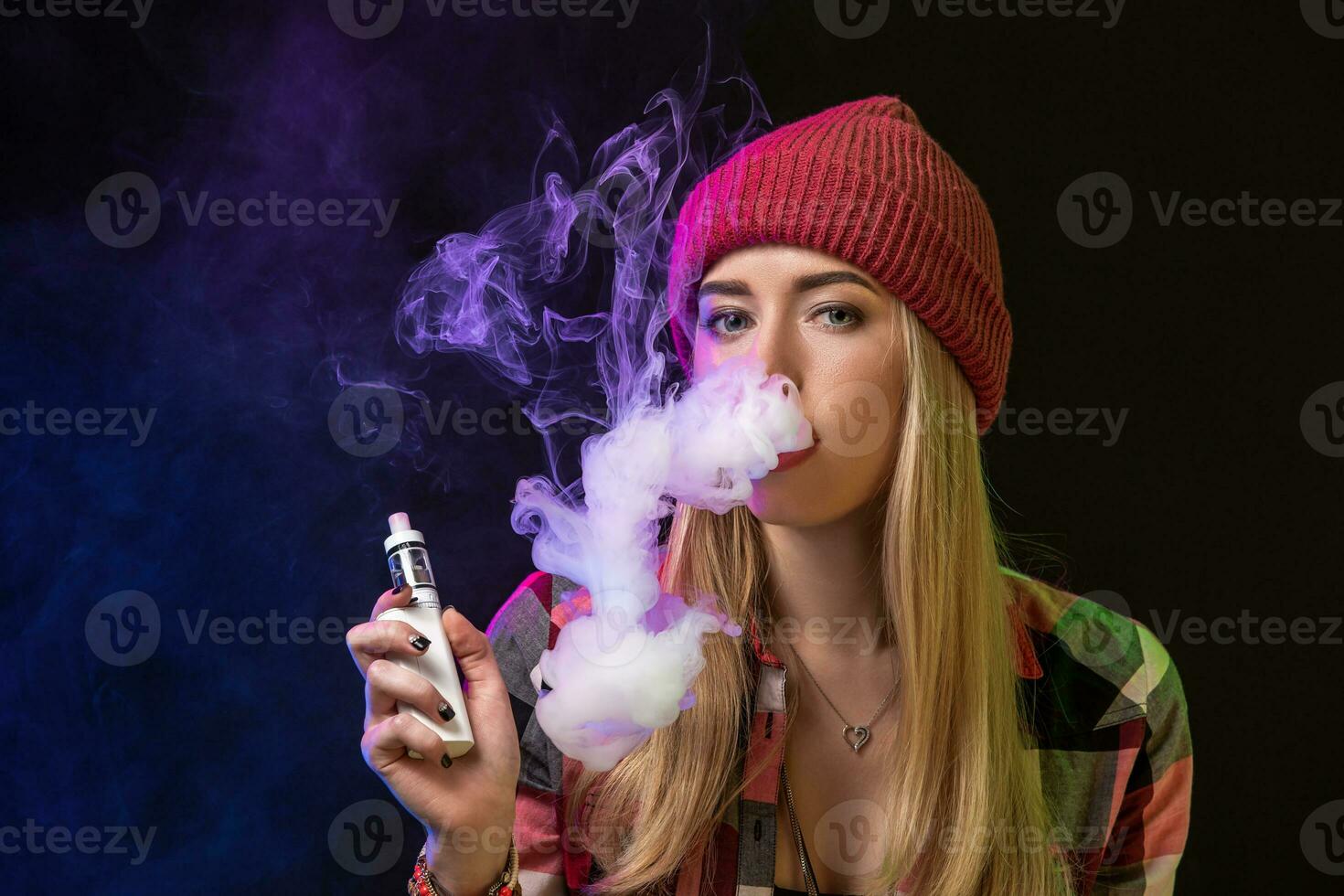 Vaping girl. Young hipster woman vape e-cig on studio on black background. Hip-hop style. Close up. photo