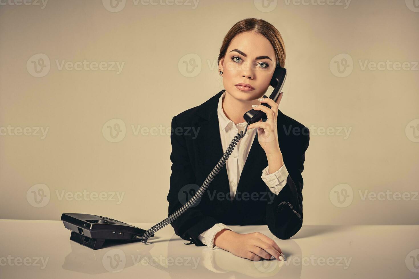 attractive dark-haired woman dressed in a black suit is sitting photo