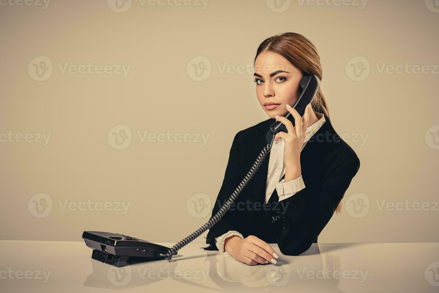 attractive dark-haired woman dressed in a black suit is sitting photo