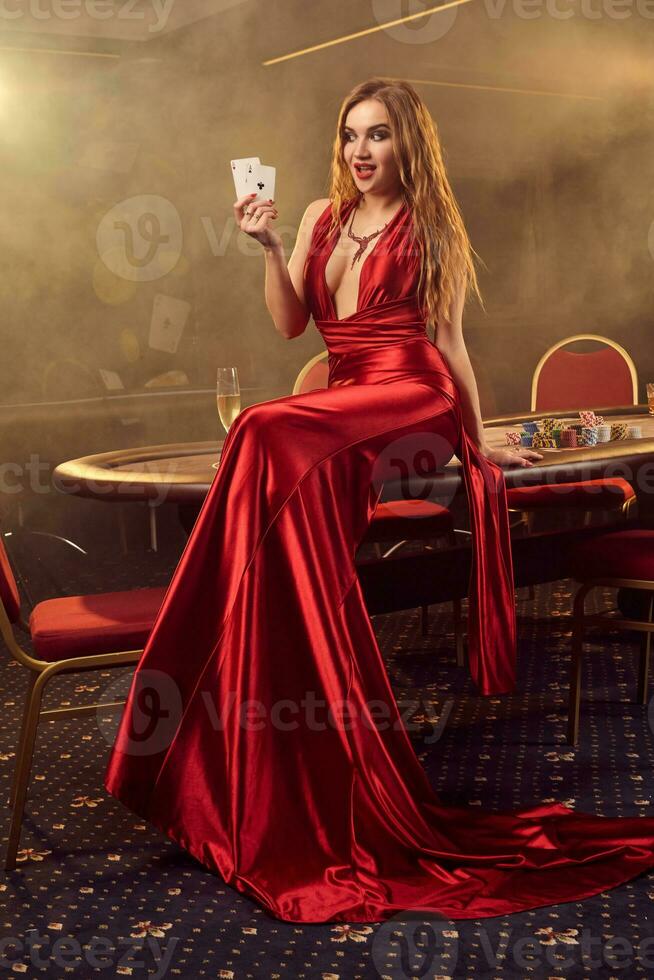 Young beautiful woman is posing against a poker table in luxury casino. photo
