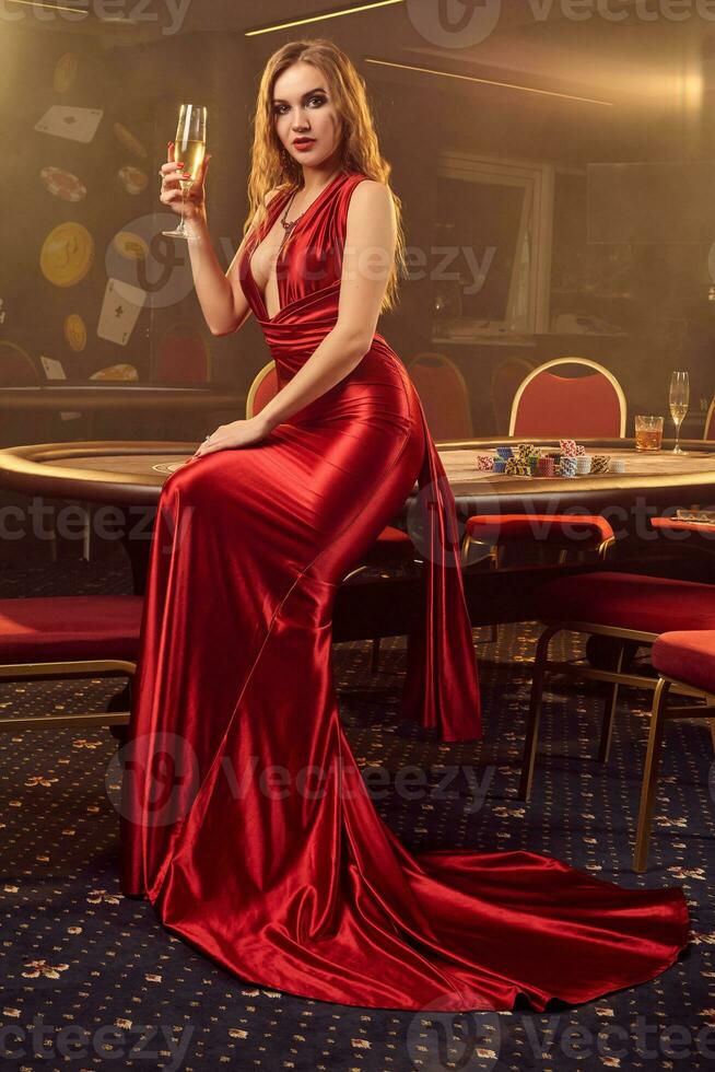 Young beautiful woman is posing against a poker table in luxury casino. photo