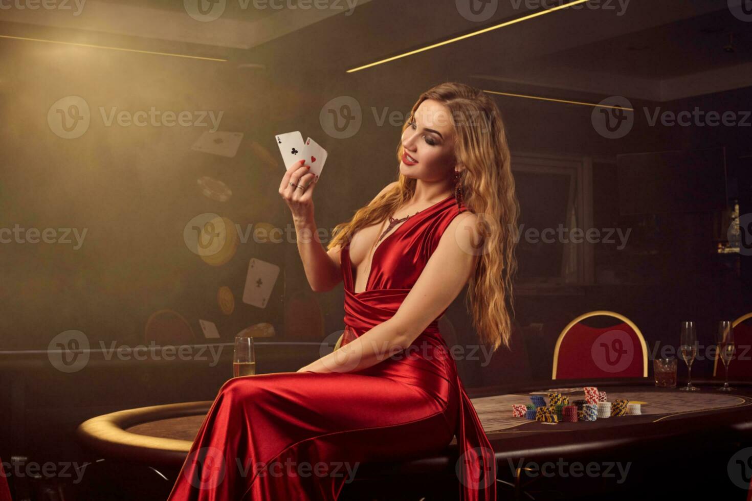 Young beautiful woman is posing against a poker table in luxury casino. photo