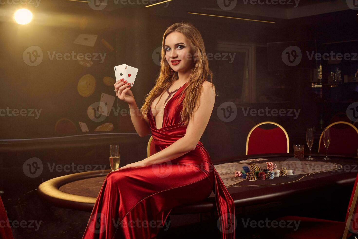 Young beautiful woman is posing against a poker table in luxury casino. photo