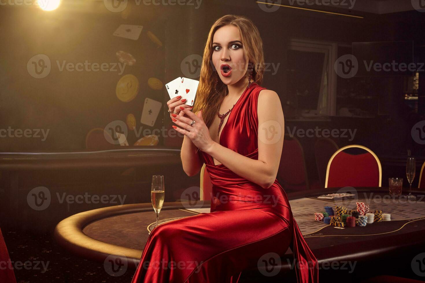 Young beautiful woman is posing against a poker table in luxury casino. photo