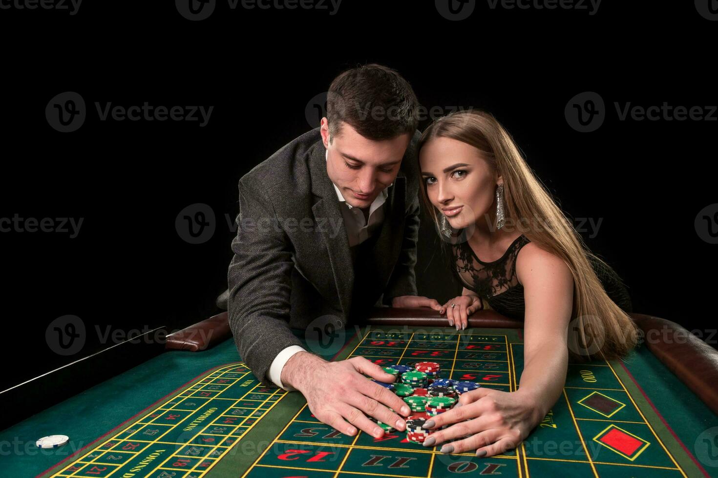 joven hermosa Pareja toma su ganancias a el ruleta mesa a el casino foto