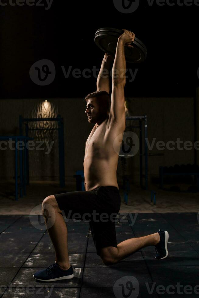 joven muscular aptitud masculino modelo haciendo pesa estocada ejercicios en el parque. foto