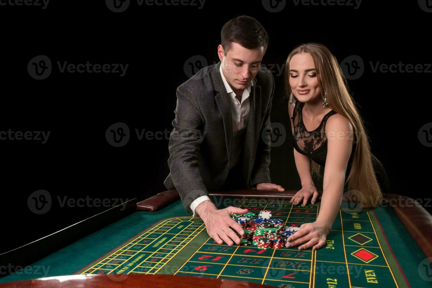 Young beautiful couple takes their winnings at the roulette table at the casino photo