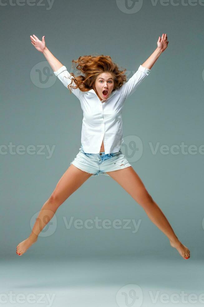 Beautiful jumping girl isolated on blue background photo