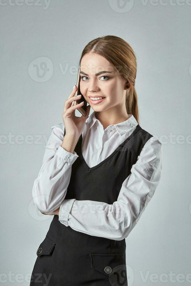 Young girl talking at the cellphone on a gray background photo