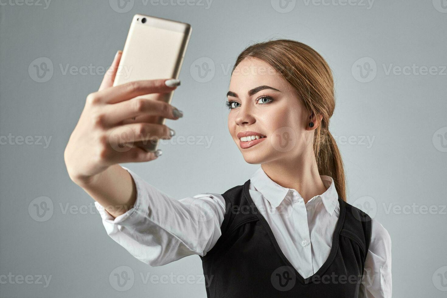 Portrait of young caucasian business woman in suit doing selfie on the phone. photo