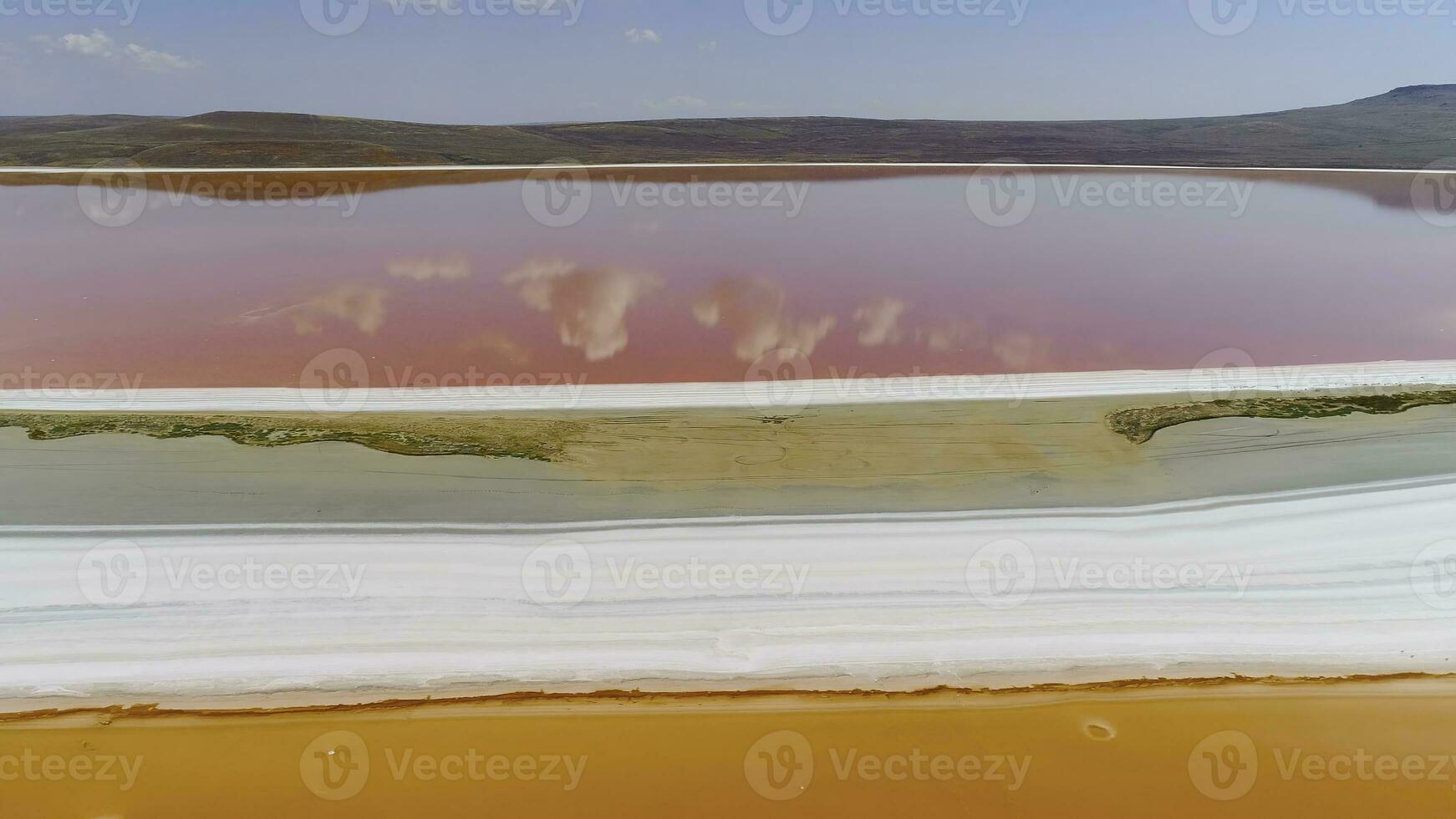 Top view of clouds reflected in pink lake. Shot. Bright colorful orange and pink lakes are separated by white shore. Beautiful reflection of clouds and blue sky in pink lake photo