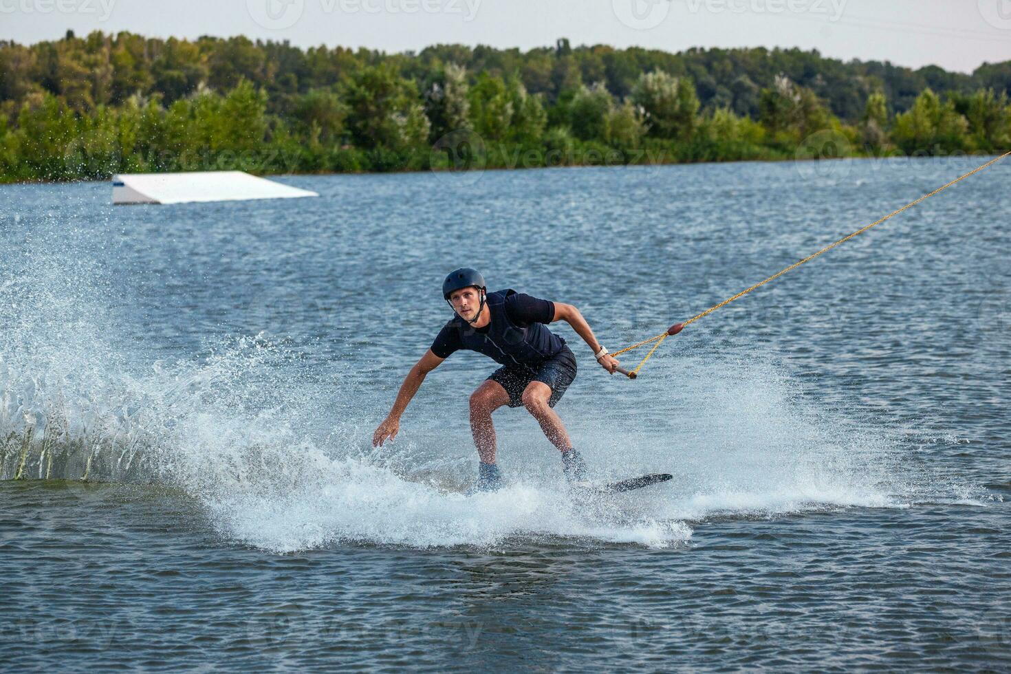 Man balancing on wakeboard towed on cable trying to make grab of board photo