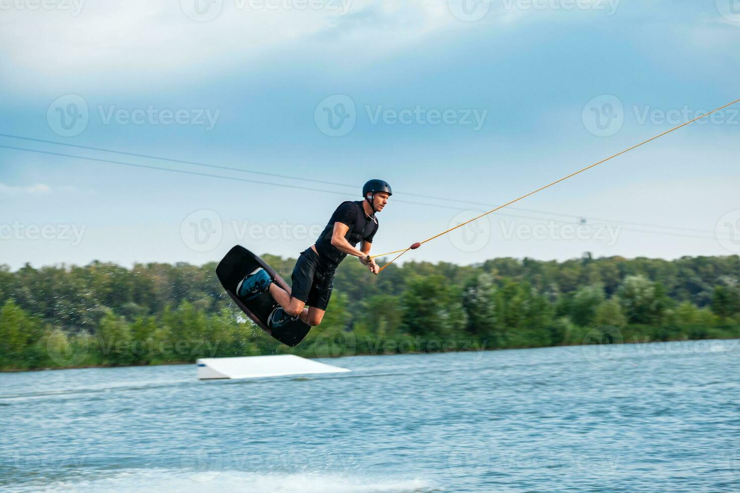 Man practicing technique of jumping over water during wakeboarding training photo