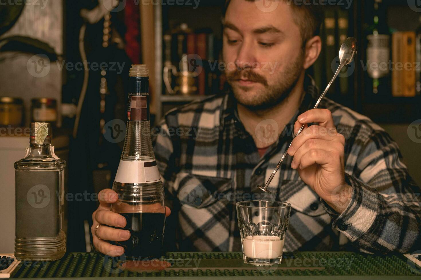 Focused bartender preparing alcoholic cocktail White Russian behind bar counter photo