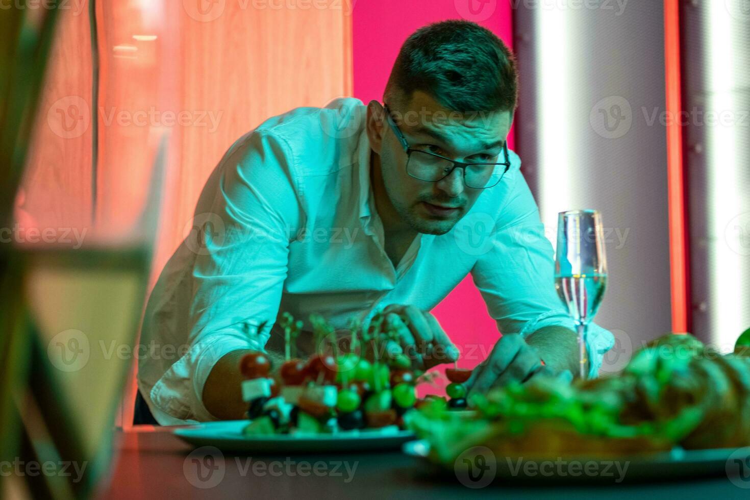 Interested man preparing snacks for home friendly party in kitchen photo