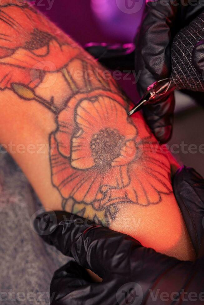 profesional creando de brillante amapolas tatuaje en hembra mano foto