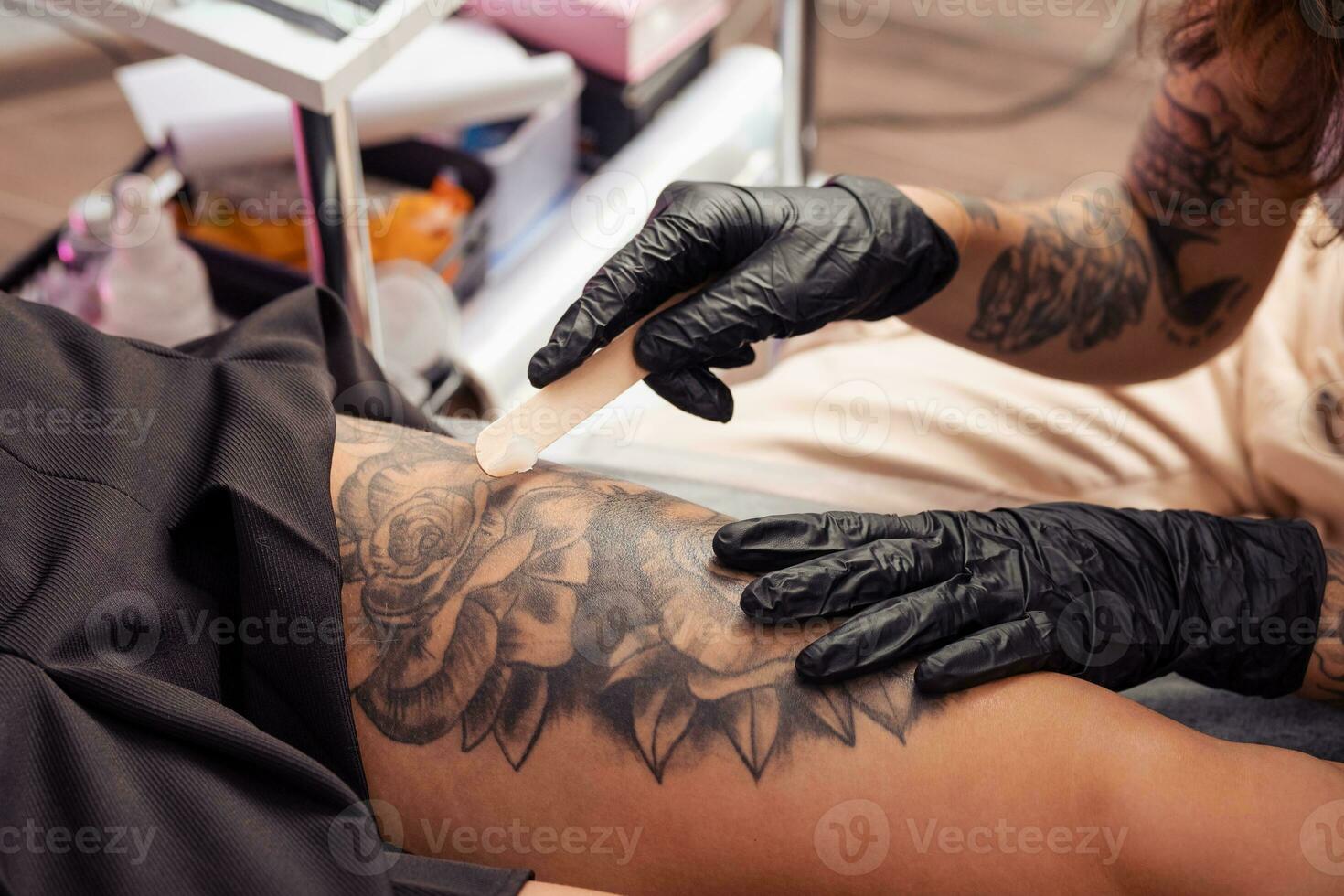 Experienced tattoo master applying healing cream on tattooed skin photo