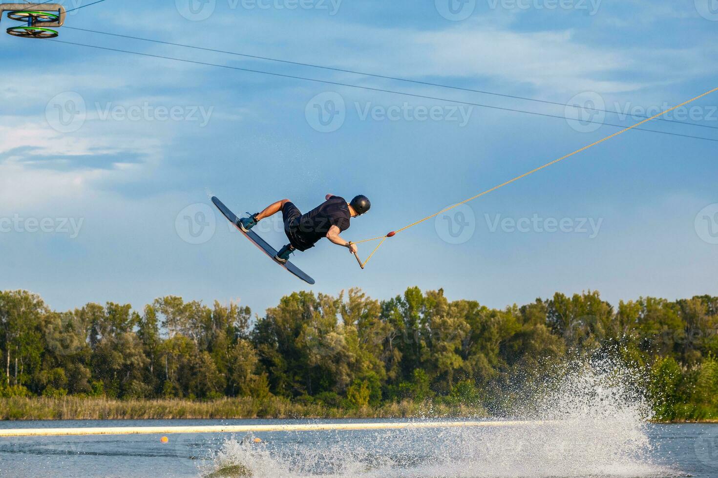 Young man skilfully making tricks on wakeboard on sunny day photo