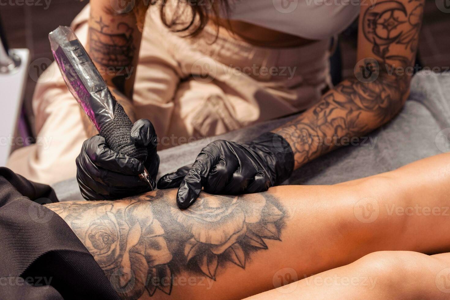 Professional tattoo master creating artistic masterpiece on female thigh photo