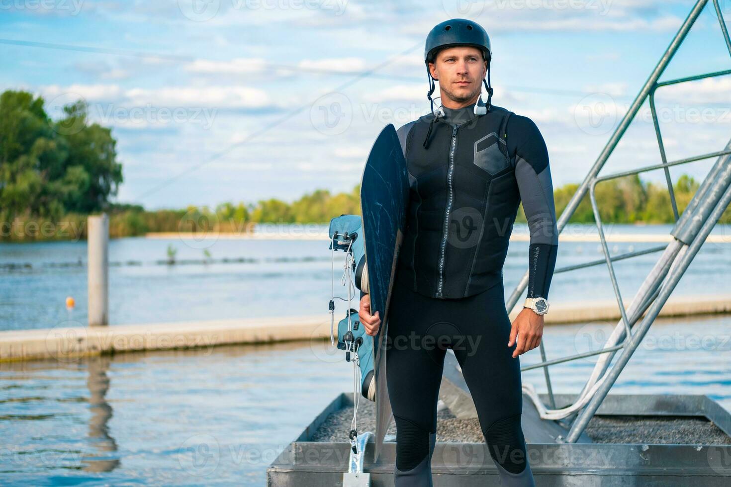 Confident wakeboarder standing on pier with board in hand photo
