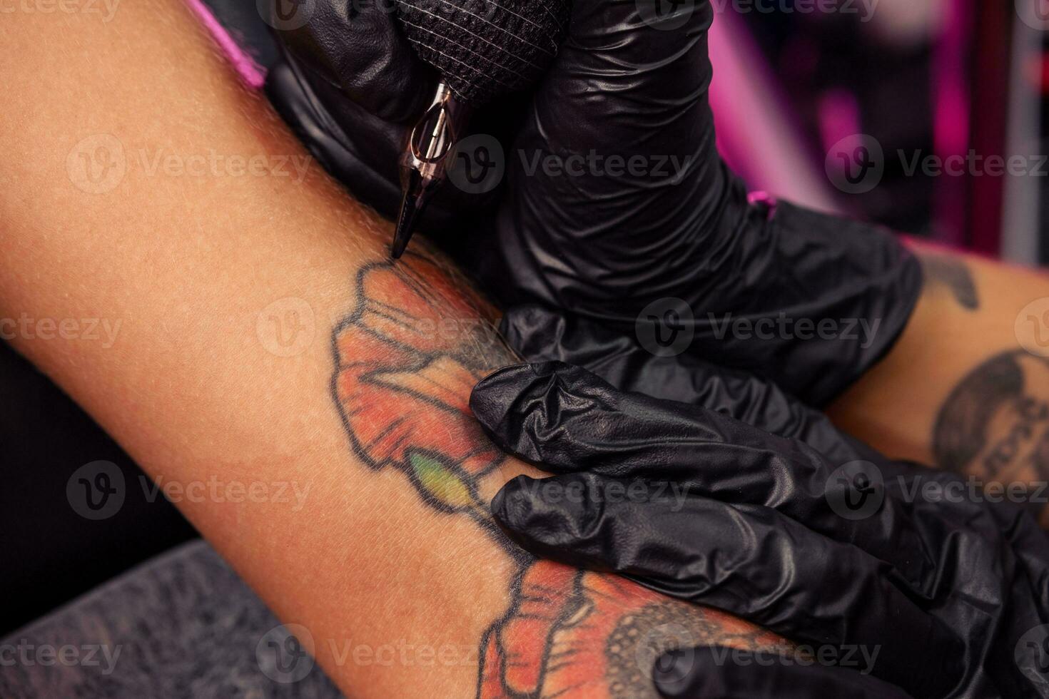 Creation of colorful poppies tattoo on female arm using tattooing machine photo