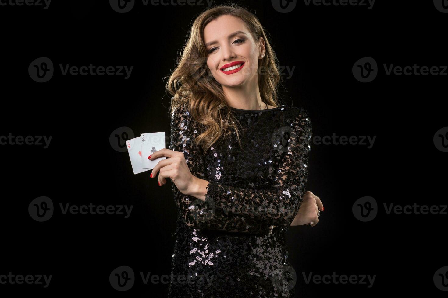 Young woman holding playing cards against a black background photo