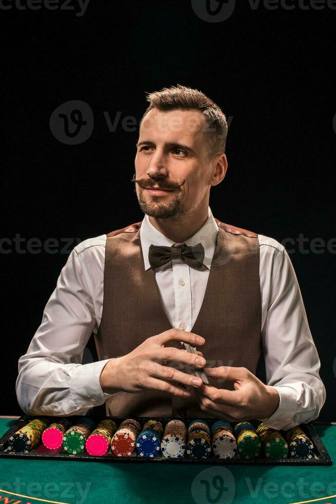 retrato de un crupier es participación jugando tarjetas, juego papas fritas en mesa. negro antecedentes foto