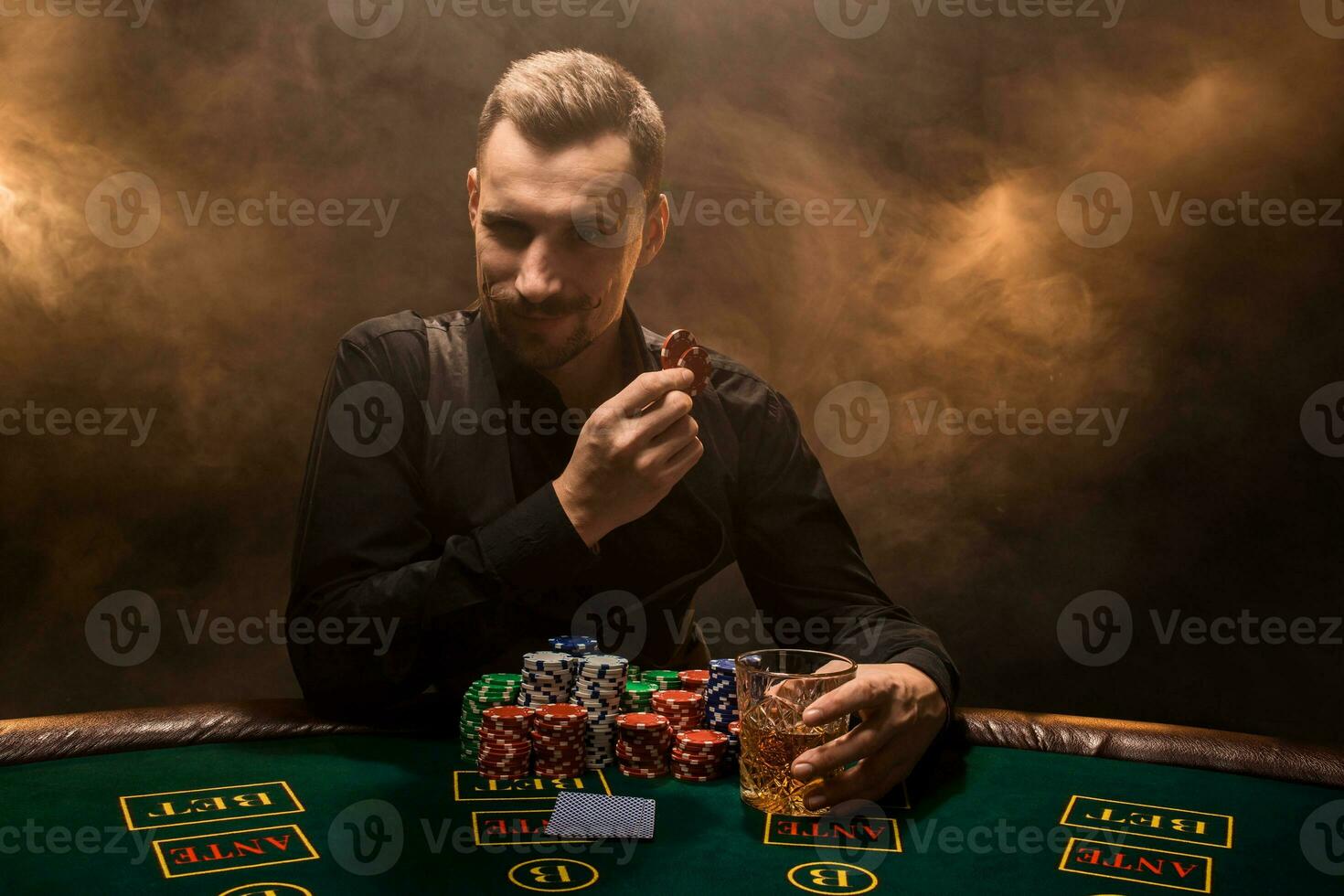 A young man in a business suit sitting at the poker table. Man gambles. The player at the gaming table playing cards. photo