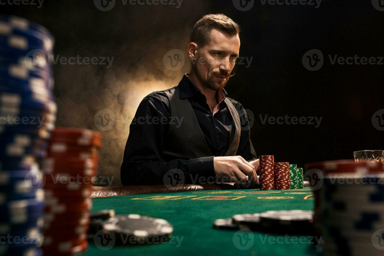Young handsome man sitting behind poker table with cards and chips photo