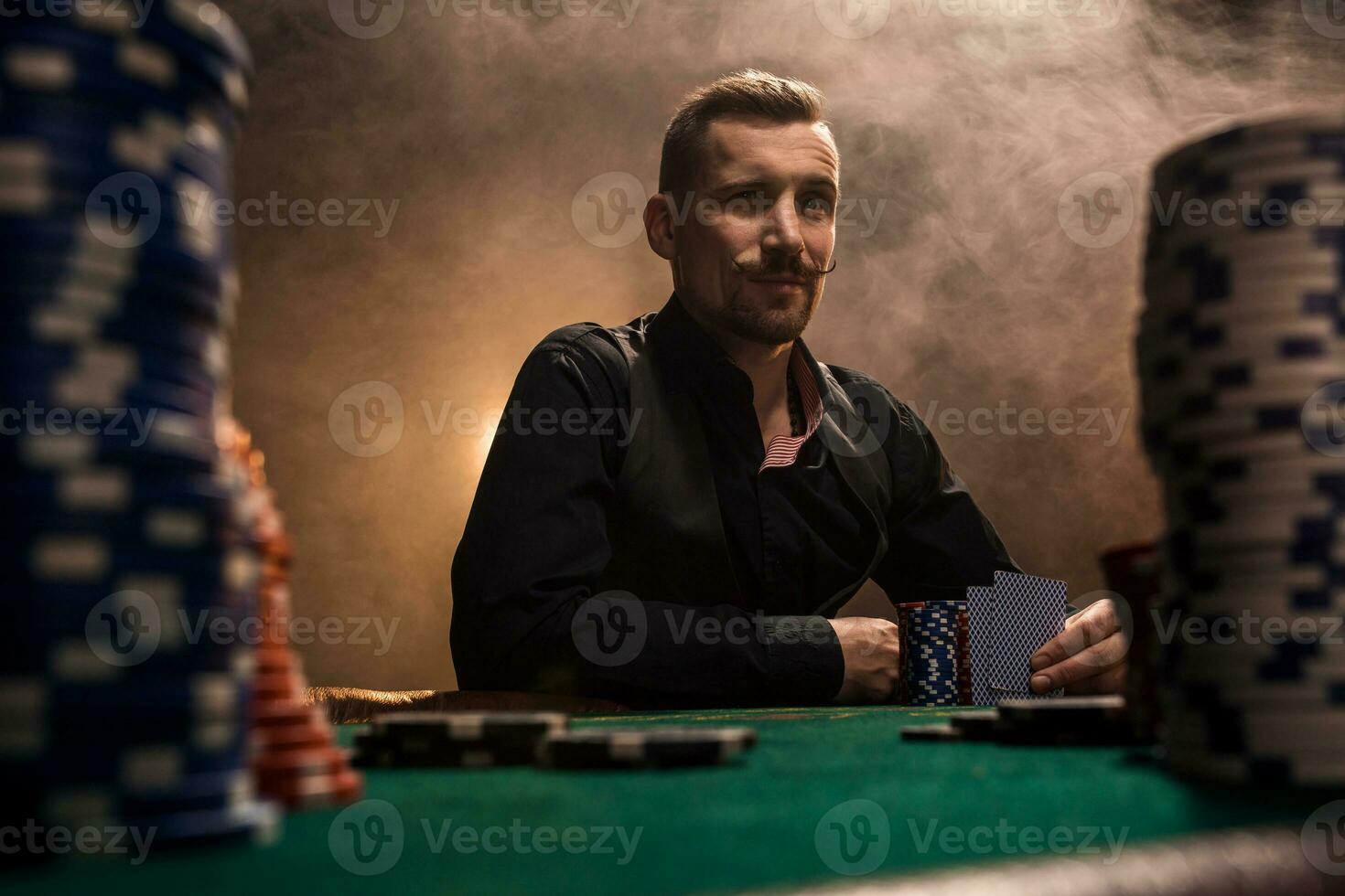 Young handsome man sitting behind poker table with cards and chips photo