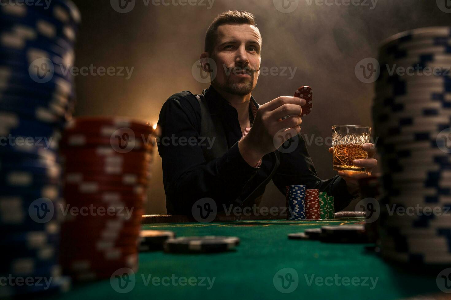 joven hermoso hombre sentado detrás póker mesa con tarjetas y papas fritas foto