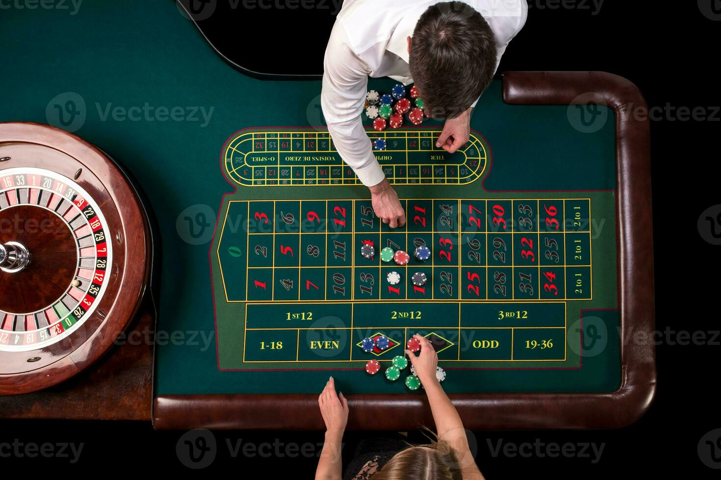 Man croupier and woman playing roulette at the table in the casino. Top view at a roulette green table with a tape measure. photo