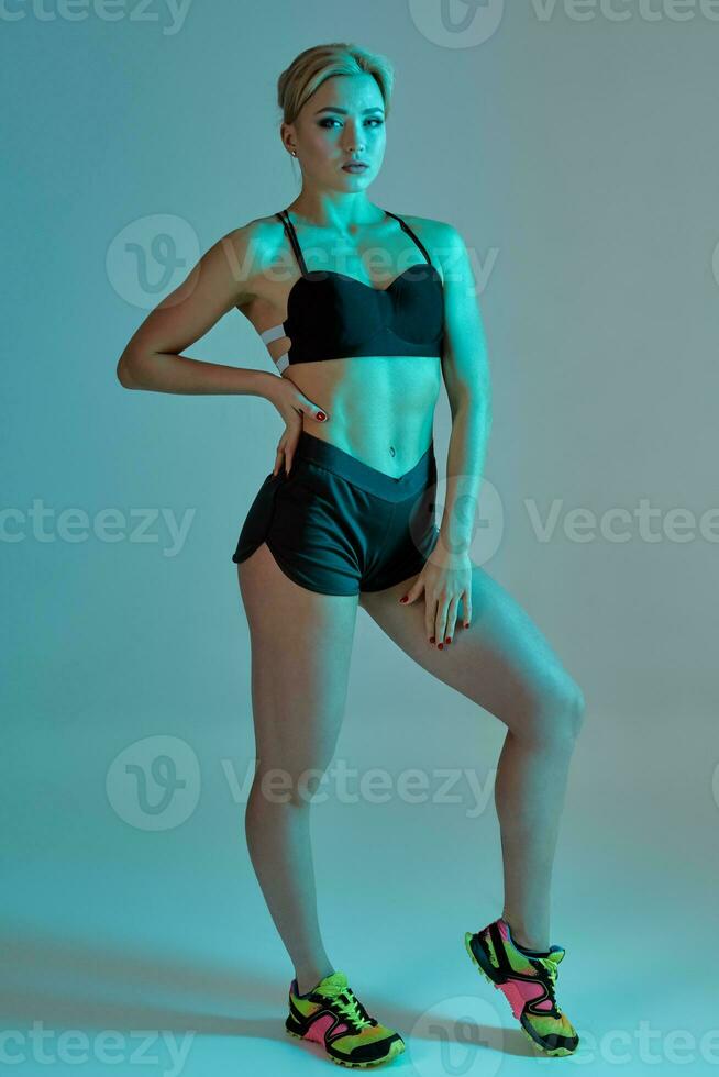 Fitness woman in black tank top and shorts, studio shot. photo